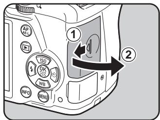 PENTAX K50 - Faites glisser la trappe de protection du logement de la carte dans le sens de la flèche, puis soulevez-la pour l'ouvrir (①→②). - 1
