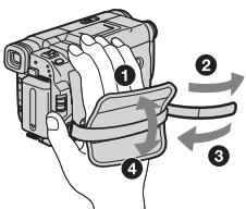 Diagram showing a hand holding a digital camera with four labeled parts and directional arrows indicating motion or movement.