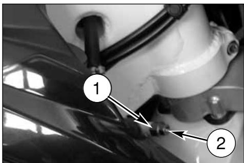 Close-up mechanical diagram showing two labeled components (1 and 2) with arrows pointing to a component on a surface.