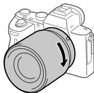 SONY ALPHA 6400 - Spingendo leggermente l'obiettivo versus la fotocamera, ruotare lentamente l'obiettivo nella direzione della freccia finché non scatta in posizione bloccata. - 1