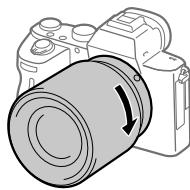 SONY ALPHA A7 III - While pushing the lens lightly toward the camera, turn the lens slowly in the direction of the arrow until it clicks into the locked position. - 1