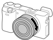 SONY A6500 - While pushing the lens lightly toward the camera, turn the lens slowly in the direction of the arrow until it clicks into the locked position. - 1