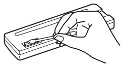 Line drawing of a hand holding a tool over a rectangular object.