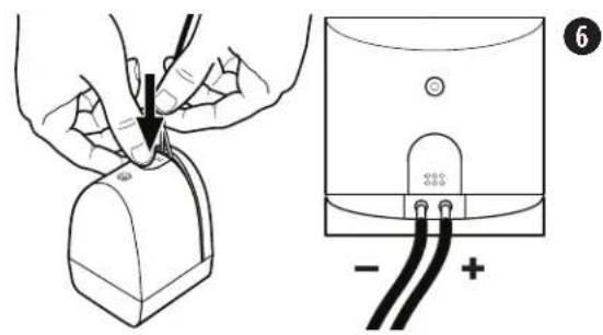 Diagram showing a hand holding a small electronic device connected to a device with labeled terminals and polarity indicators.