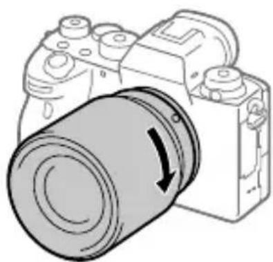 SONY Alpha A9 II - Spingendo leggermente l'obiettivo versus la fotocamera, ruotare lentamente l'obiettivo nella direzione della freccia finché non scatta in posizione bloccata. - 1