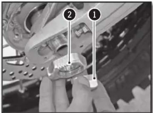 Close-up of hands holding a mechanical component with numbered callouts (1, 2) pointing to specific parts.