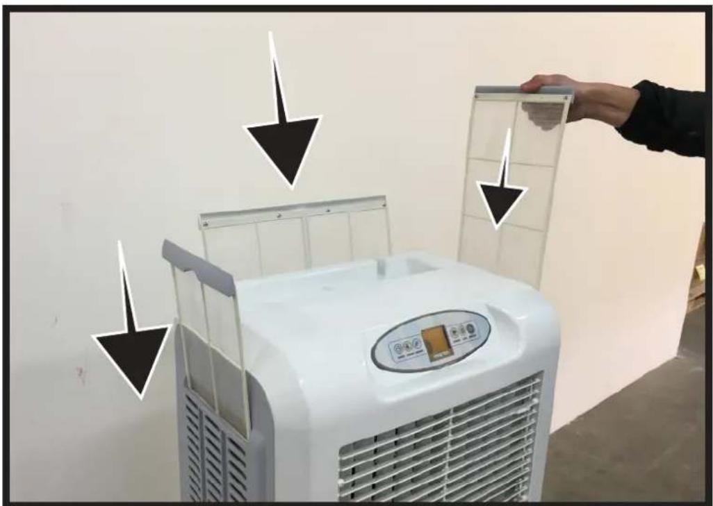 Photo of a white air conditioner unit with Chinese annotations pointing to its lid and panel, indicating cleaning or installation steps.