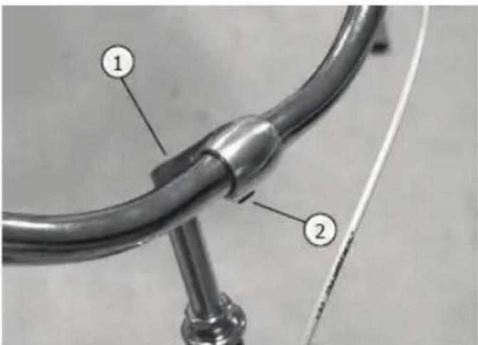Close-up of a metallic pipe fitting with numbered annotations pointing to components
