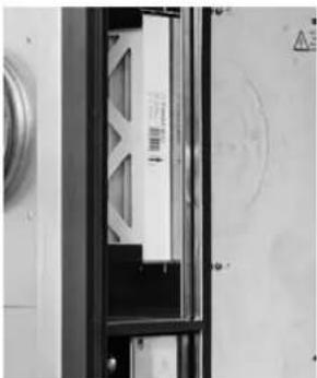 Interior view of a mechanical or electrical enclosure with a white panel and black frame (no visible text or symbols)