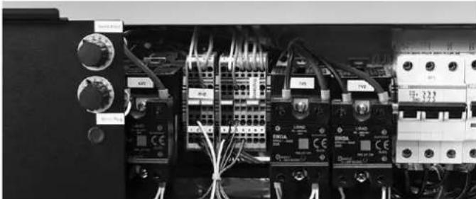 Interior view of an electrical control panel with multiple circuit breakers and wiring (no visible text or labels)