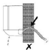 Diagram showing a pipe connection with labeled components and an arrow indicating direction, alongside a brick wall and a cross symbol.
