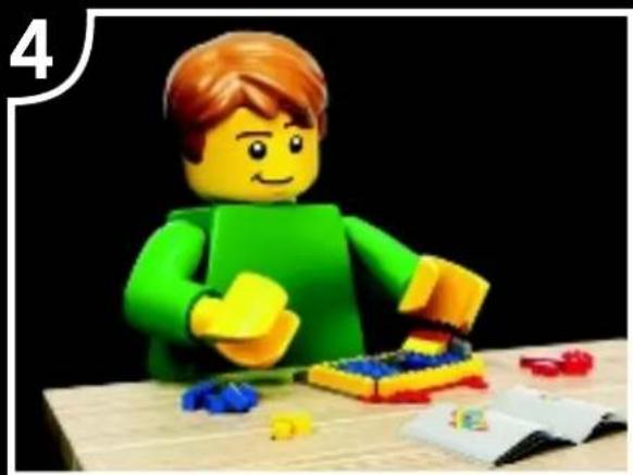 Lego figure in green shirt and yellow shorts assembling a blue and red LEGO block at a wooden table (no text or symbols visible)