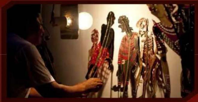 Person arranging colorful shadow puppets on a wall, no visible text or symbols