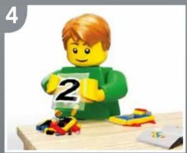 Lego figure in green shirt holding number 2, surrounded by small toys and a computer (no text or symbols)
