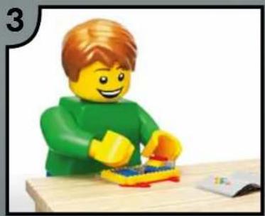 Lego figure in green hoodie assembling a small object at a wooden table (no text or symbols visible)