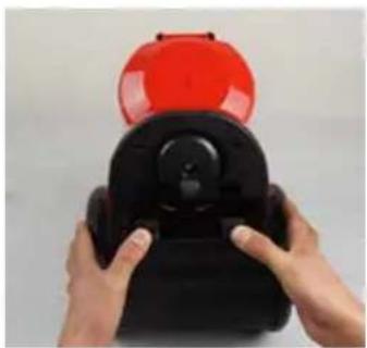 Close-up of hands holding a black device with a red cap on top (no visible text or symbols)