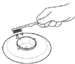 Hand using a tool to clean or inspect a circular component (no text or symbols visible)