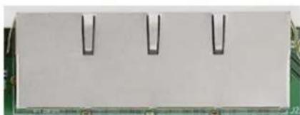 Close-up of a white rectangular electronic component with three black U-shaped pins, placed on a green circuit board (no visible text or symbols)