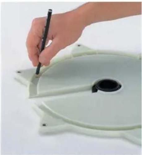 Hand holding a pen next to a white plastic disc with a black hole, no visible text or symbols