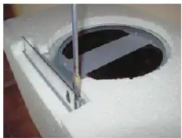 Close-up of a circular concrete structure with a vertical metal rod inserted, showing internal dark and white patterns (no text or symbols visible)