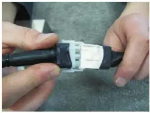 Close-up of hands assembling a black and white plastic connector (no text or symbols visible)
