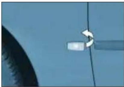 Close-up of a car's side panel with a white arrow pointing to the handle (no text or symbols visible)