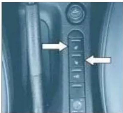 Close-up of a car interior panel with directional arrows pointing to specific buttons (no text or symbols visible)