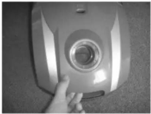 Hand holding a camera lens on a flat surface (no text or symbols visible)