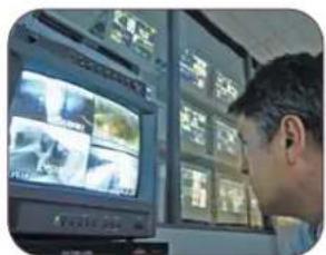 Person viewing surveillance camera feeds on a wall-mounted monitor, with multiple video thumbnails visible