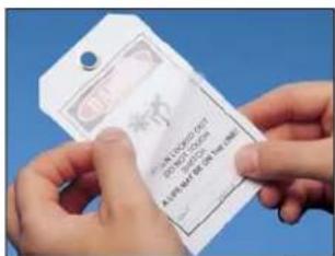 Hand holding a white tag with printed text and QR code, against a blue background