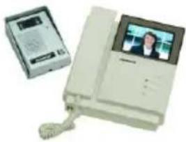 White office phone with a digital display showing a person's photo, next to a small electronic device (no visible text or symbols)