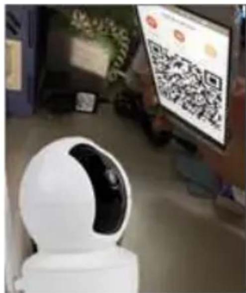 Street photo with visible store signboards and a robot interacting with a digital display showing QR code