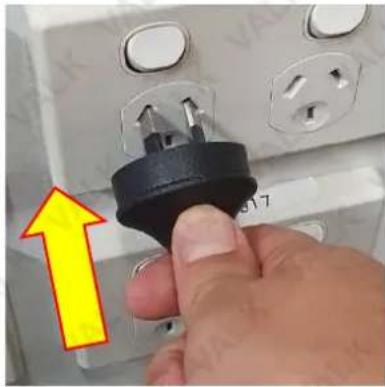 Close-up of a hand inserting a black plastic plug into an electrical socket (no text or symbols visible)