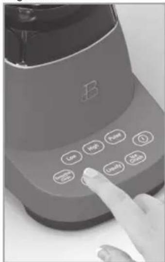 Close-up of a kitchen blender with labeled buttons and a finger pointing to the button