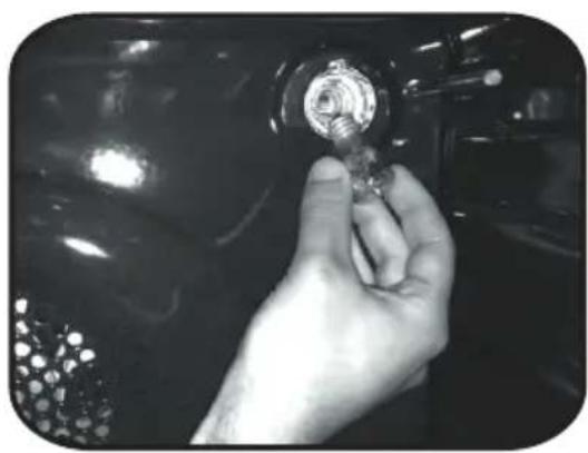 Close-up of a hand holding a small metallic object against a dark background (no visible text or symbols)