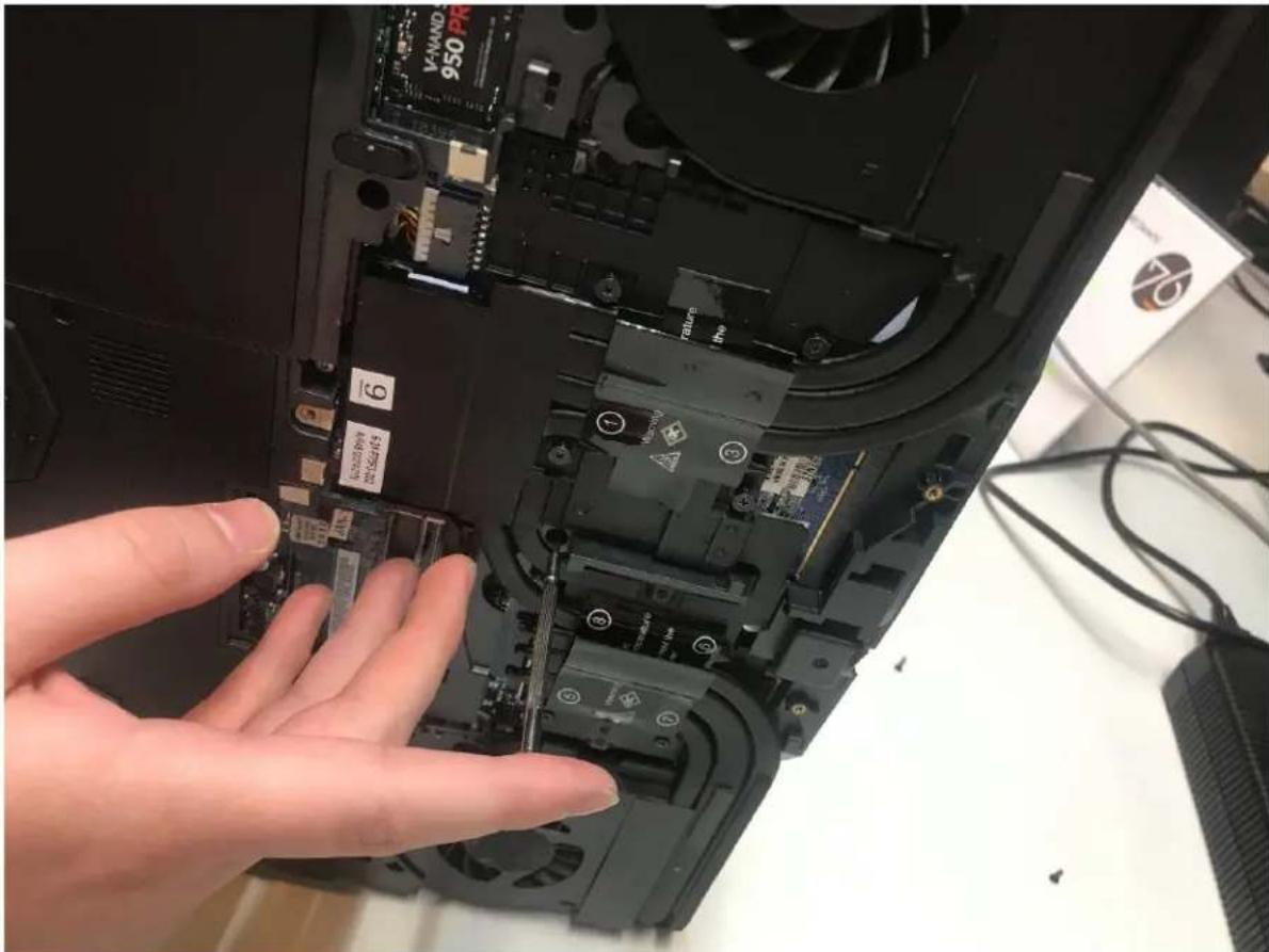 Laptop screen showing a hand inserting a component into a motherboard with visible labels like 'VANAND 950 PR' and numbered parts.