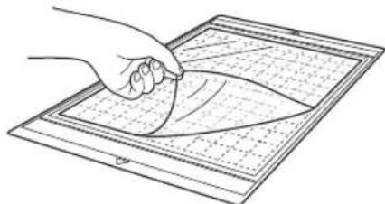 Line drawing of a hand holding a pen over a grid-patterned sheet with a leaf-like shape (no text or symbols)
