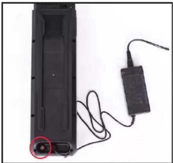 Close-up of a black electronic device with a red circular connector and connected cable, no visible text or symbols