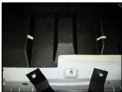 Close-up of a mechanical component with black textured surfaces and two metallic clips (no visible text or symbols)