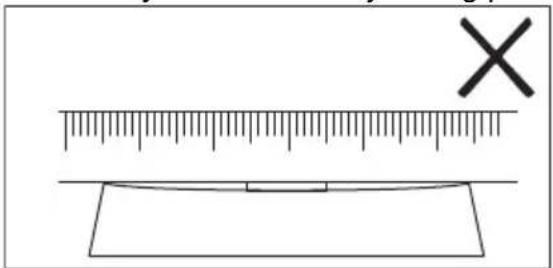 Diagram showing a ruler measuring a rectangular object with a cross mark above it, likely indicating measurement or alignment.