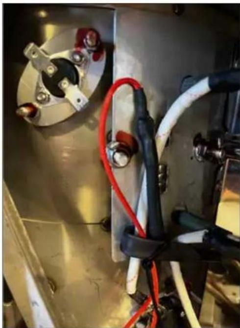 Close-up of industrial equipment with metal casing, red and blue cables, and bolts (no visible text or symbols)