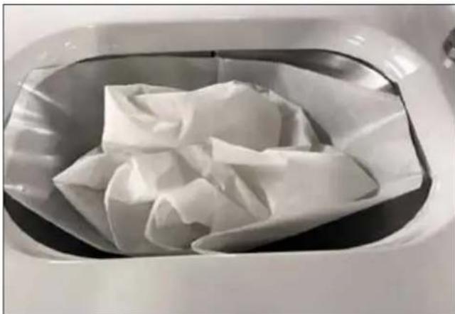 White plastic bag wrapped in paper inside a metal container (no text or symbols visible)