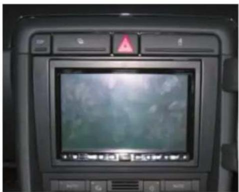 Interior view of a car dashboard with a digital display showing a blurred scene (no visible text or symbols)