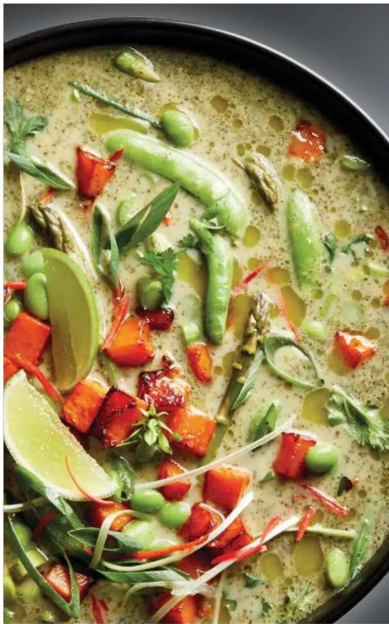 Close-up of a bowl of creamy soup with vegetables, beans, and garnishes (no text or symbols visible)