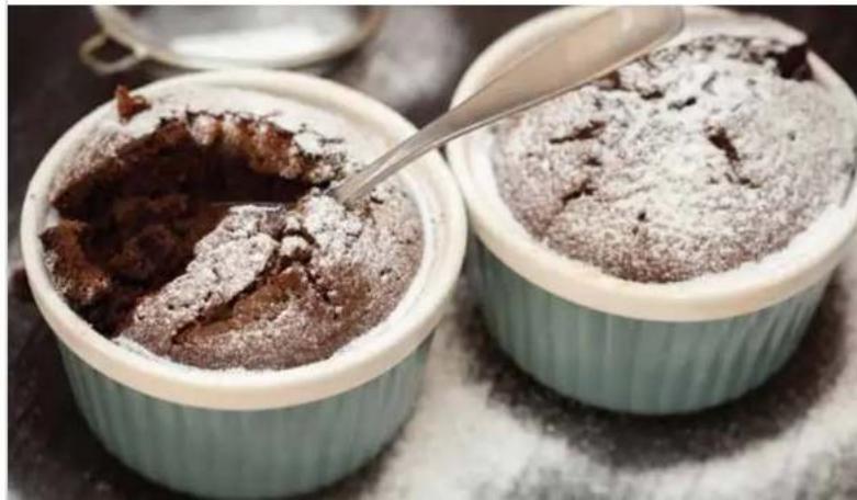Two chocolate-crumpled cakes in white ceramic cups, one being filled with powdered sugar and the other with a spoon (no text or symbols visible)