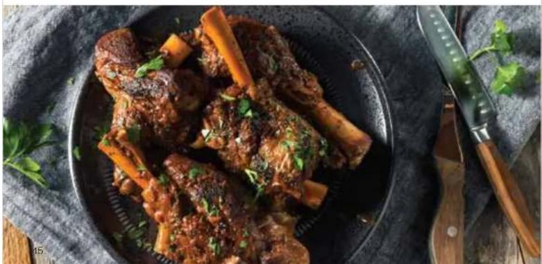 Plate of braised pork ribs with green herbs, served on a dark textured dish with chopsticks and leafy greens (no text or symbols visible)