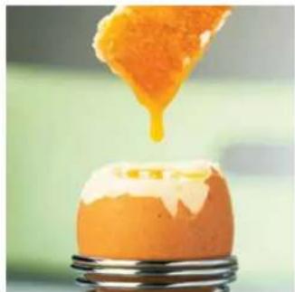 Close-up of a cracked egg with a golden liquid being poured into it, no text or symbols visible