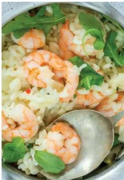 Close-up of a bowl of cooked shrimp with green leafy greens and sauce, no visible text or symbols