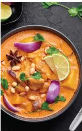 Close-up of a colorful Indian-style stew with peanuts, cilantro, and lime slices (no text or symbols visible)