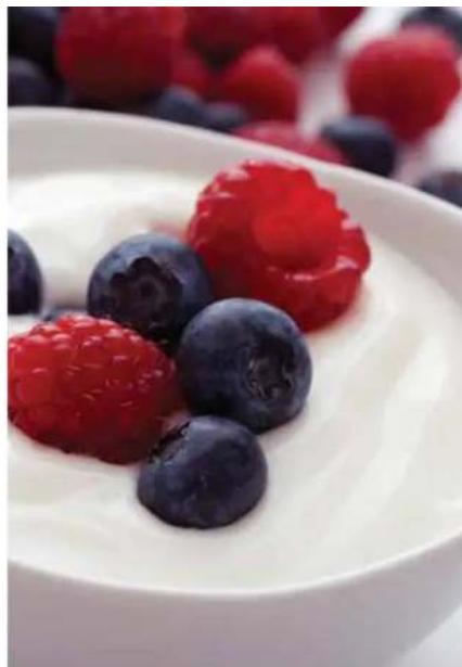 Close-up of a white bowl containing white cream with fresh berries (no text or symbols visible)